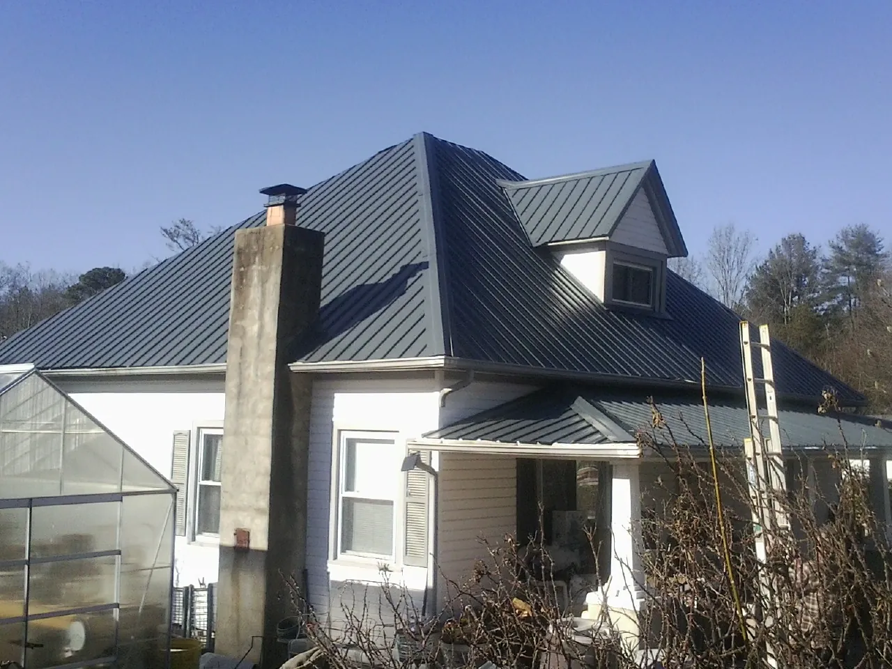 Dark blue standing seam metal roof on a white farmhouse with dormer — Slate & Tile Roof Repair by Roofing Brothers in Leetonia