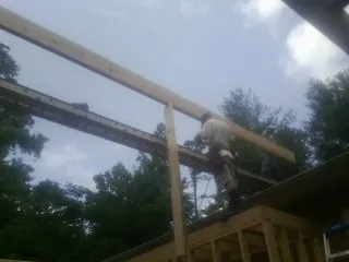 Carpenter setting a ridge beam over a new addition frame — Ice Dam Removal by Roofing Brothers in Leetonia