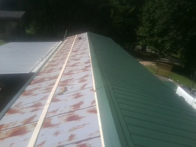 Old rusted panels beside newly installed green metal roofing — Wind Damage Roof Repair by Roofing Brothers in Leetonia