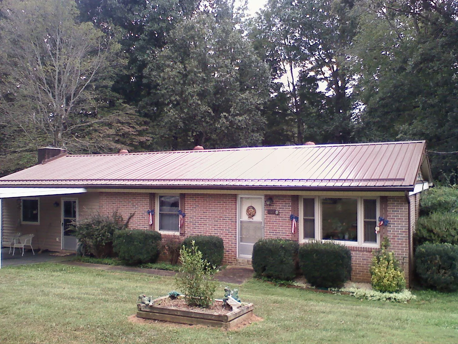 Bronze metal roof on a brick ranch home with a carport in Leetonia