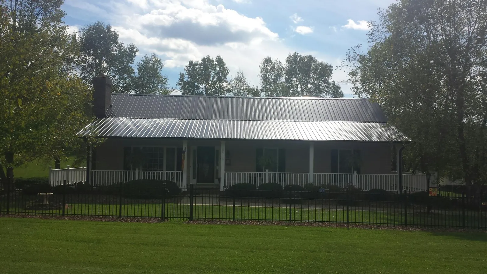 Gray metal roof on a brick ranch with a full width front porch — Gutter Guard Installation work by our crew in Leetonia