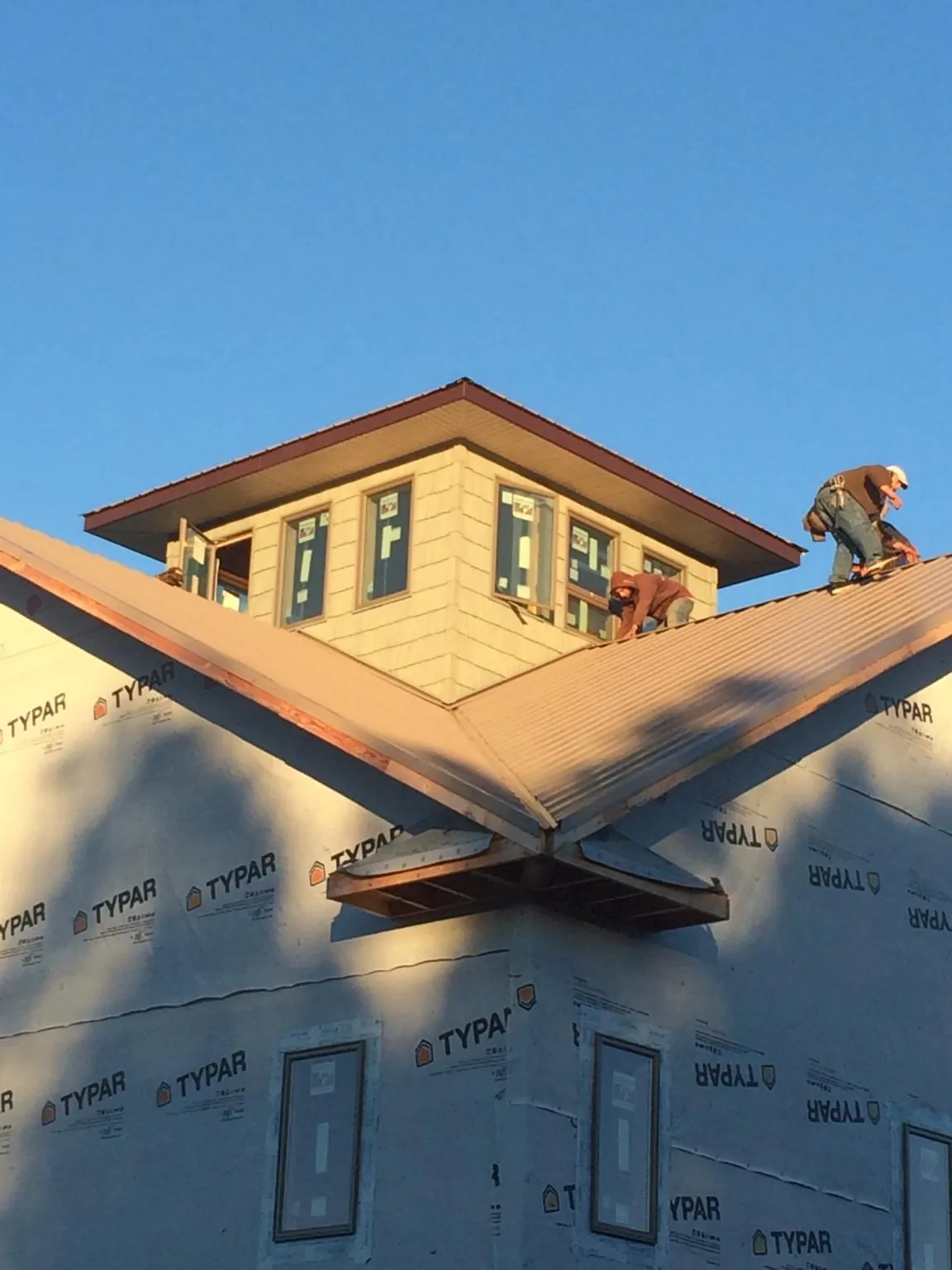 Roofers working around a rooftop cupola on a new metal roof at sunset — Roof Waterproofing in Leetonia by Roofing Brothers